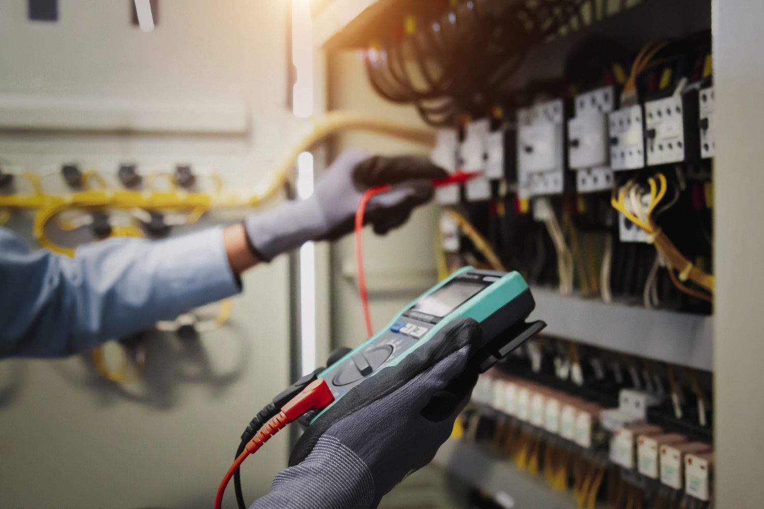 Electrician testing electrical panel with multimeter.